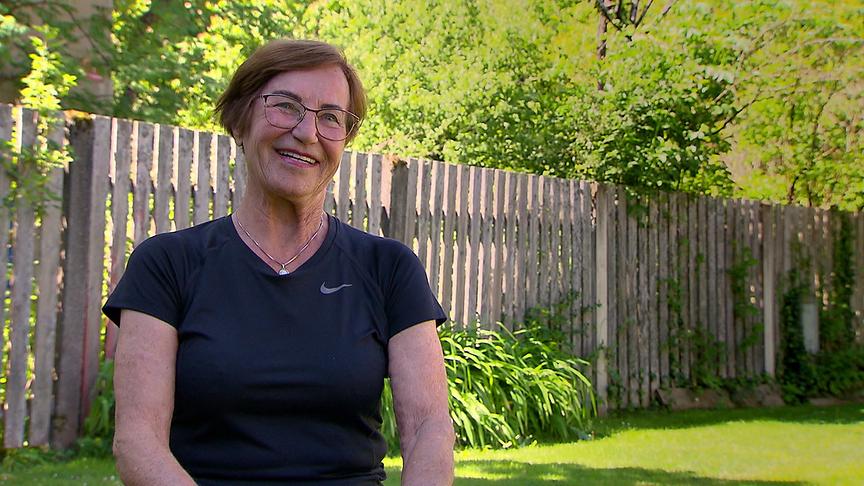 Die 82-jährige Gerda Peroutka in schwarzem Sport-Shirt sitzt in ihrem Garten beim Interview