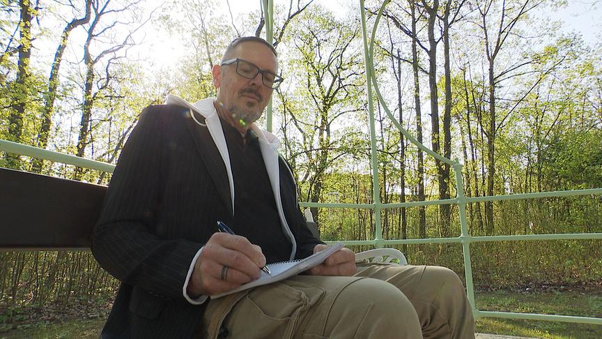 Der ehemalige Patient Franz Josef Rohrmoser, der hier in einem Park mit Notizheft und Kuli sitzt, hat bei seinem Aufenthalt im Landesklinikum Mauer seine Liebe zum Schreiben entdeckt.