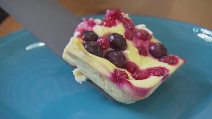 Der Topfen-Frucht-Auflauf wird mit einem Messer auf ein blaues Teller gelegt.