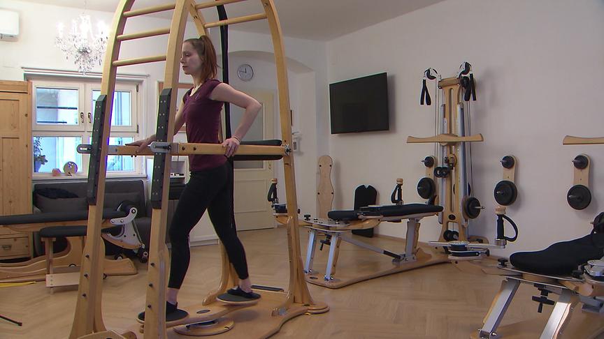 Eine Frau trainiert an einem Gyrotonic-Gerät aus Holz in einem hellen Raum 