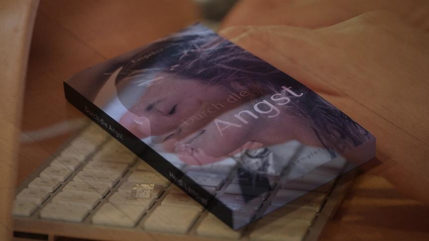 Ein Buch mit dem Titel „Durch die Angst“ liegt auf einer Tastatur.