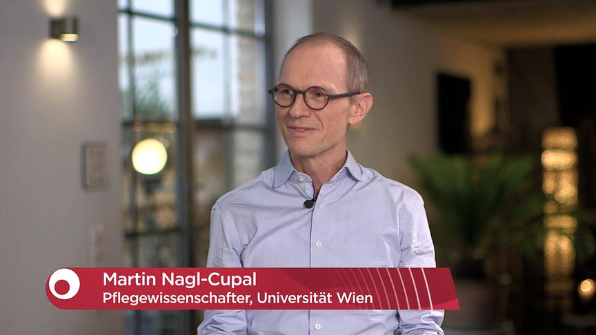 Dr. Martin Nagl-Cupal wird in einem Interview gezeigt, begleitet von einer grafischen Einblendung mit seinem Namen und seiner beruflichen Funktion als Pflegewissenschafter an der Universität Wien.
