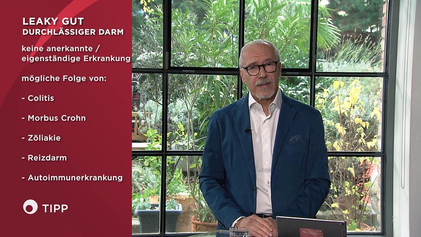 Prof. Dr. Siegfried Meryn steht im Studio vor einem großen Fenster, während links im Bild Informationen über „Leaky Gut“ und mögliche Ursachen eingeblendet sind.