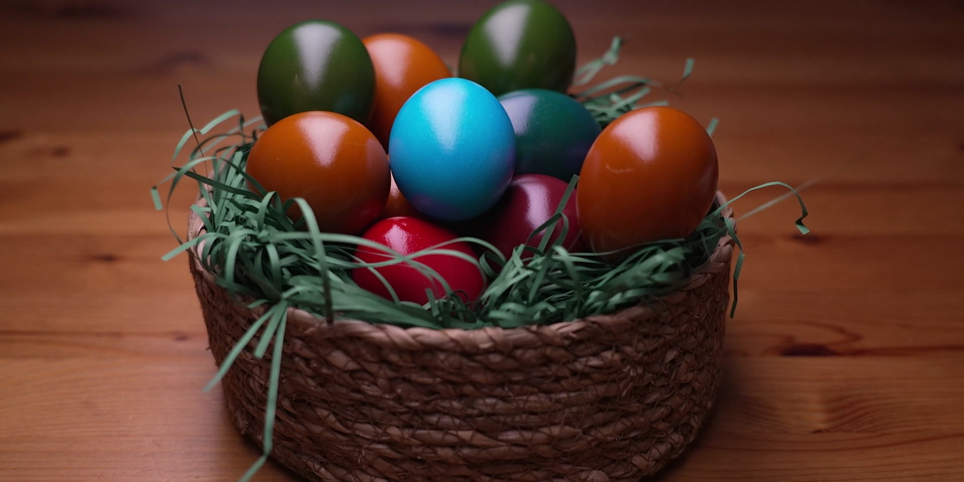 Ein Osterkörbchen mit bunt gefärbten Eiern auf einem Holztisch