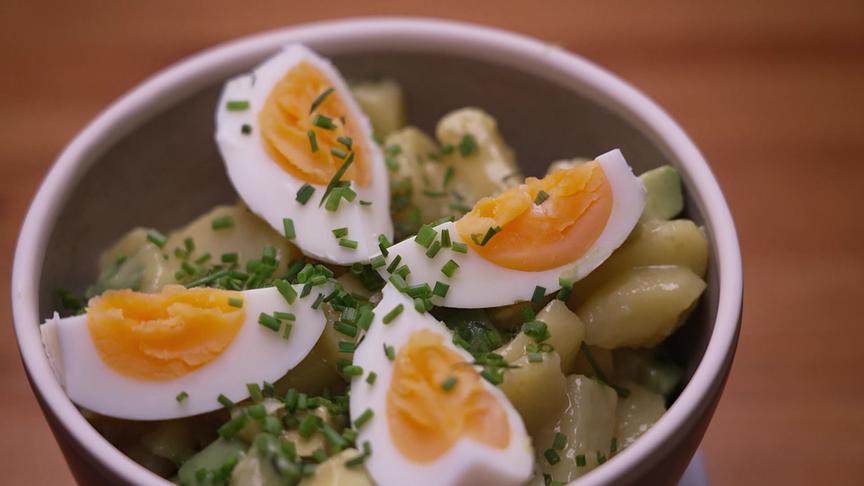 Ein Avocado-Ei-Kartoffelsalat ist mit geviertelten gekochten Eiern und Schnittlauch garniert.
