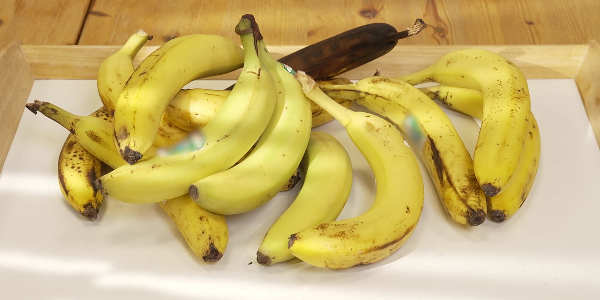 Auf einem Tablett liegt ein Haufen unterschiedlich reifer Bananen.