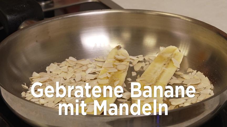 In einer Pfanne werden halbierte Bananen zusammen mit Mandelsplittern angebraten.