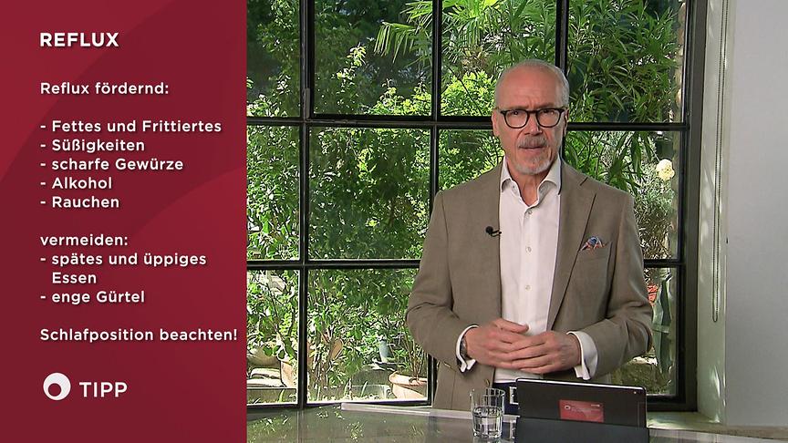 Prof. Dr. Siegfried Meryn steht an einem Tisch im Studio und gibt Tipps zu Reflux, die grafisch links eingeblendet sind.