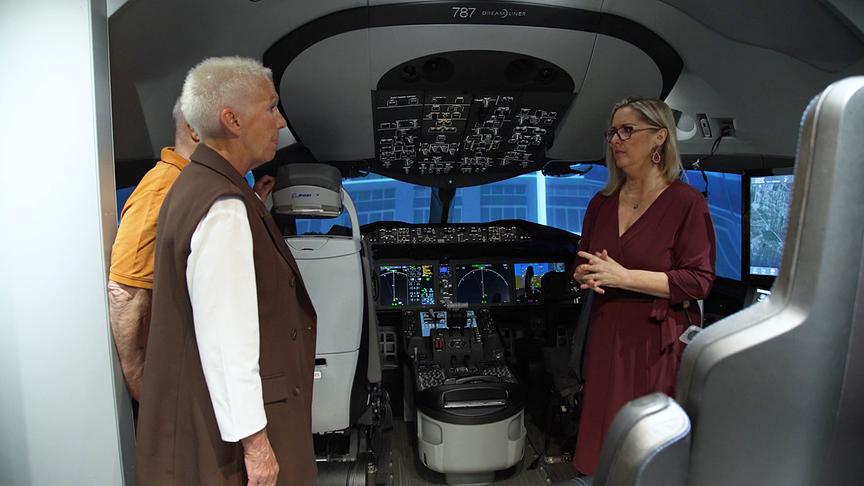 Mehrere Personen stehen in einem Flugsimulator‑Cockpit einer Boeing 787.