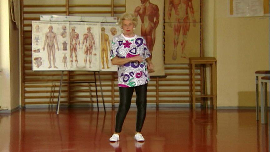 Ilse Buck steht in einem Raum mit anatomischen Schautafeln und macht Bewegungsübungen.