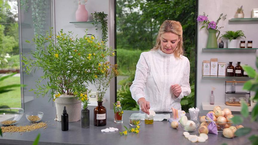 Christine Reiler tunkt in einer hellen Küche ein Wattepad in Johanniskrautöl.
